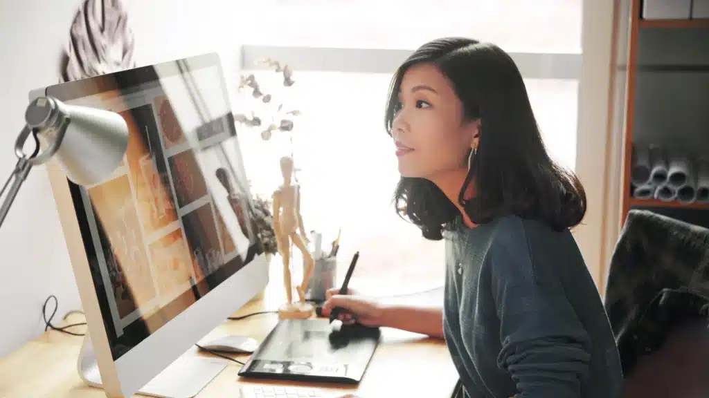 A female chiropractor sits at her desk working on a computer, focused on the screen in her clinic office. This image represents digital marketing for chiropractors and the importance of a chiropractor marketing agency in guiding online visibility.