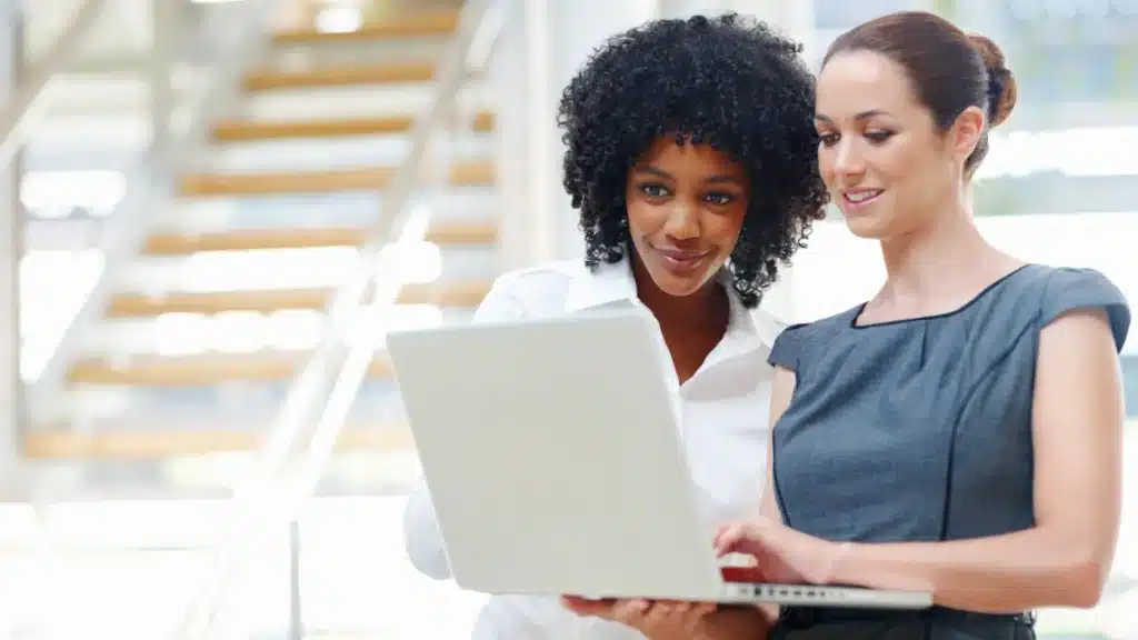 Two women collaborating on a laptop, discussing strategies to improve online reputation and business reviews.