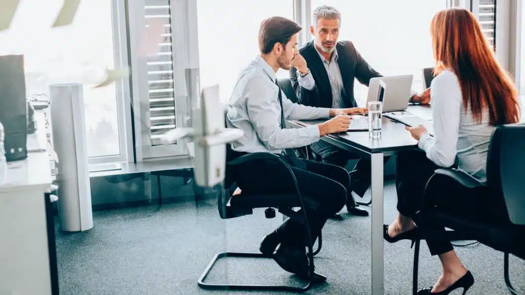 Marketing team collaborating with laptops around a table, planning HIPAA-certified content strategy.